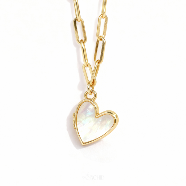 Gold mother-of-pearl heart locket necklace on white background
