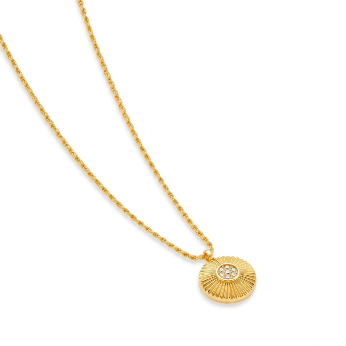 Rae Medallion Necklace, necklace laid at an angle showing the fluted sunburst disc and cubic zirconia centre on the rope chain