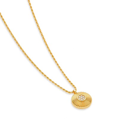 Rae Medallion Necklace, necklace laid at an angle showing the fluted sunburst disc and cubic zirconia centre on the rope chain