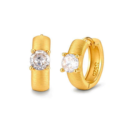 Juno Solitaire Huggies, pair of brushed gold huggie hoops, one seen front-on with a four-prong cubic zirconia, one angled showing the S925 stamp inside the hoop