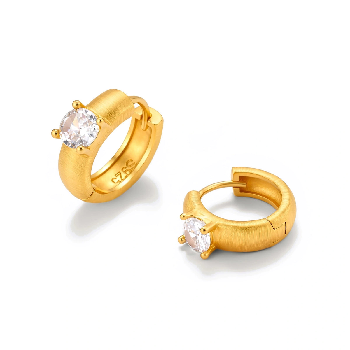 Juno Solitaire Huggies, one huggie hoop tilted to show the prong-set cubic zirconia, one with the hinged snap closure open