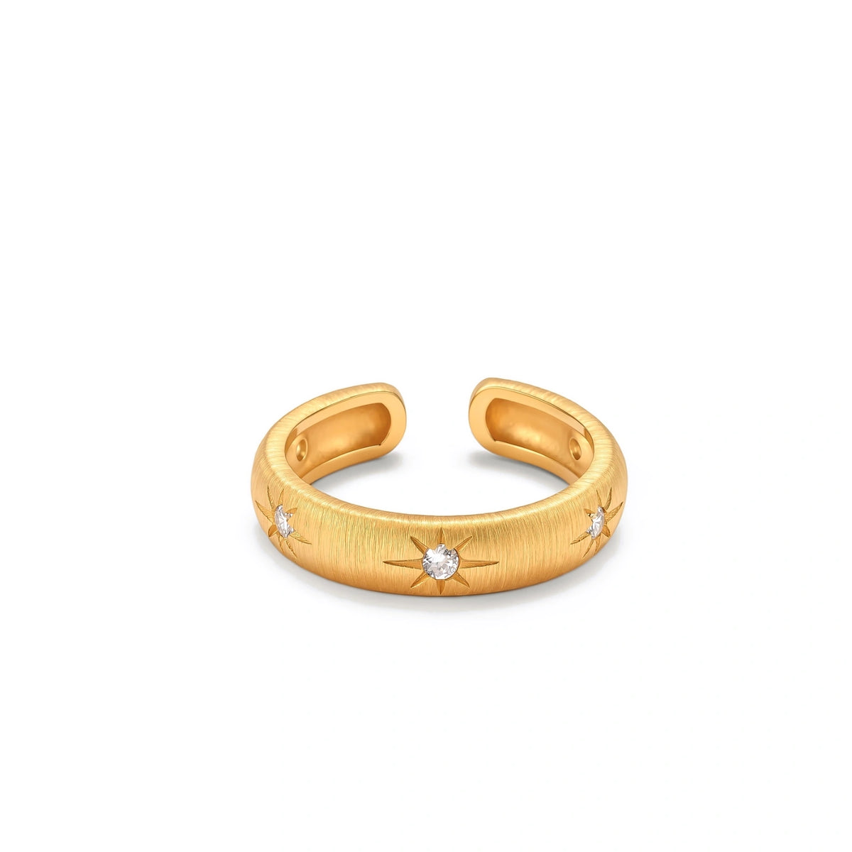 Astra Cuff Ring, brushed gold open cuff ring lying on its side, viewed from above, showing three starburst-set cubic zirconia along the band and the opening