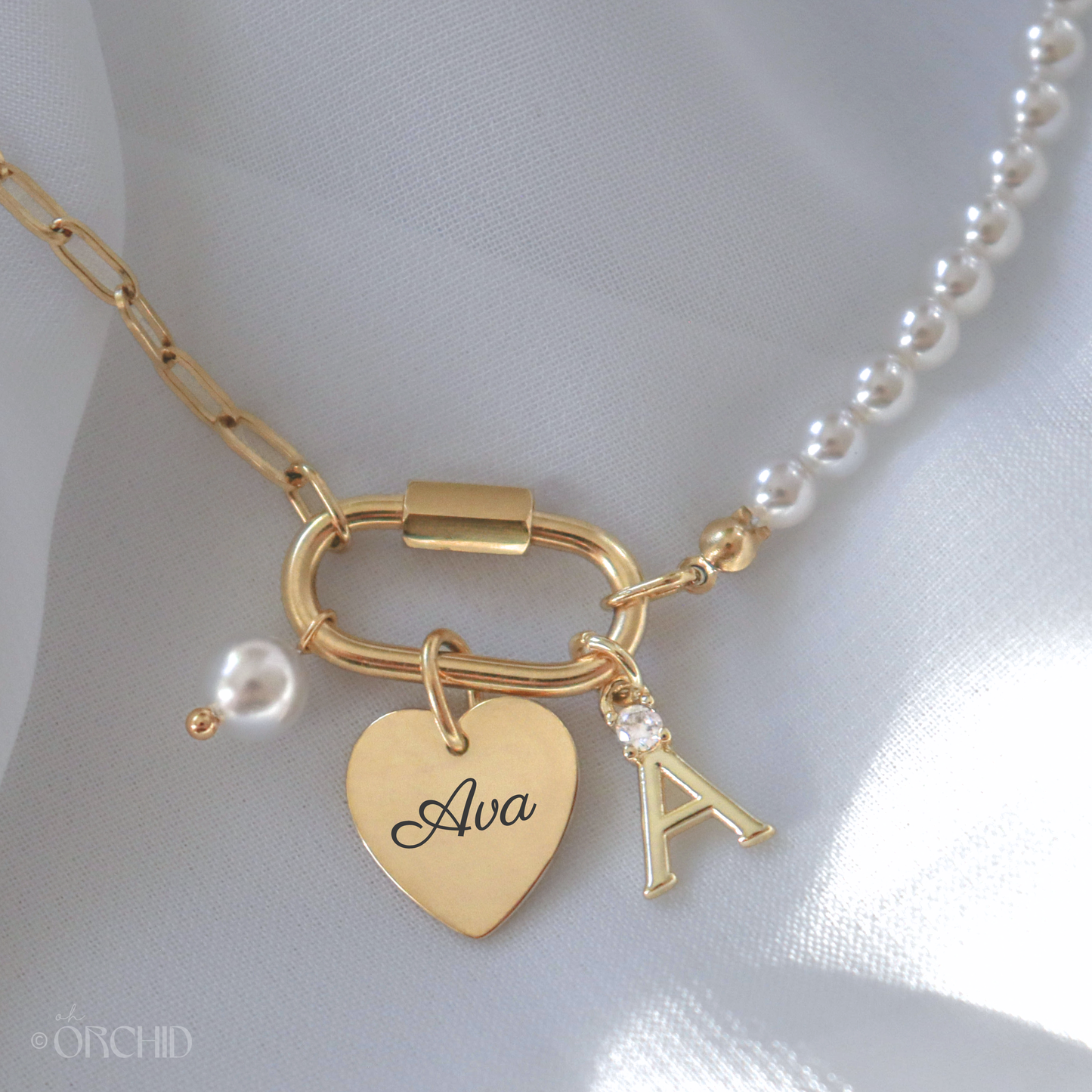 Gold pearl carabiner charm necklace with heart-shaped 'Ava' tag and letter 'A' charm.