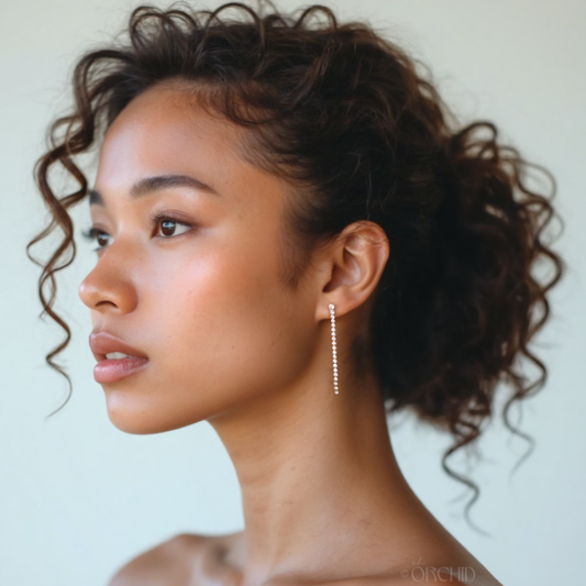 Woman with styled hair and earrings against a neutral background