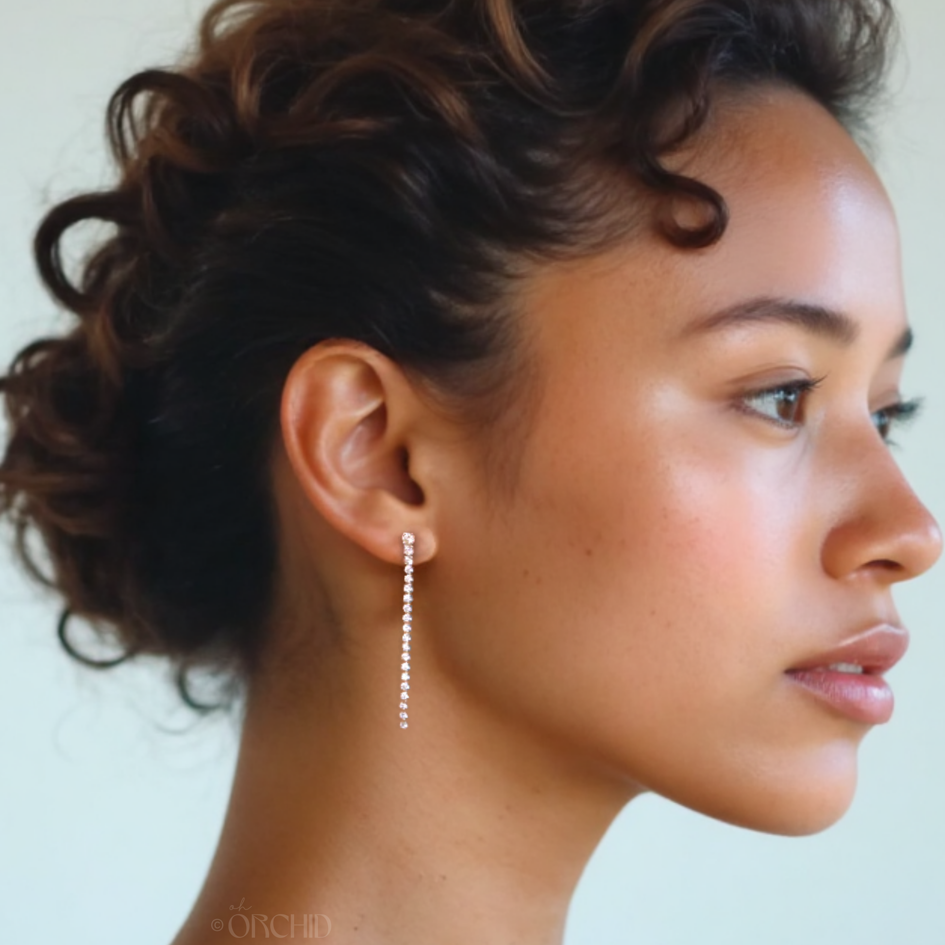 Close-up of a woman's profile with a pearl earring against a neutral background