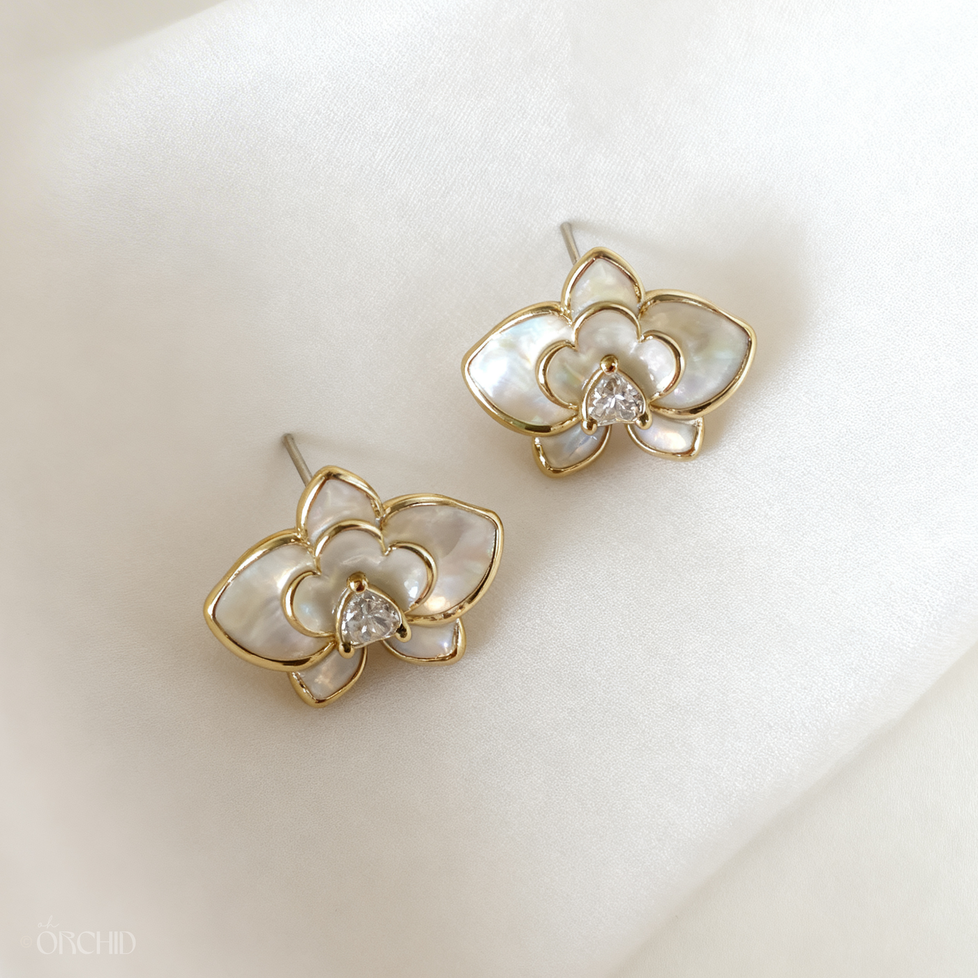 Gold and pearl flower-shaped earrings on a soft white background