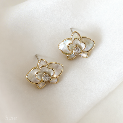 Gold and pearl flower-shaped earrings on a soft white background