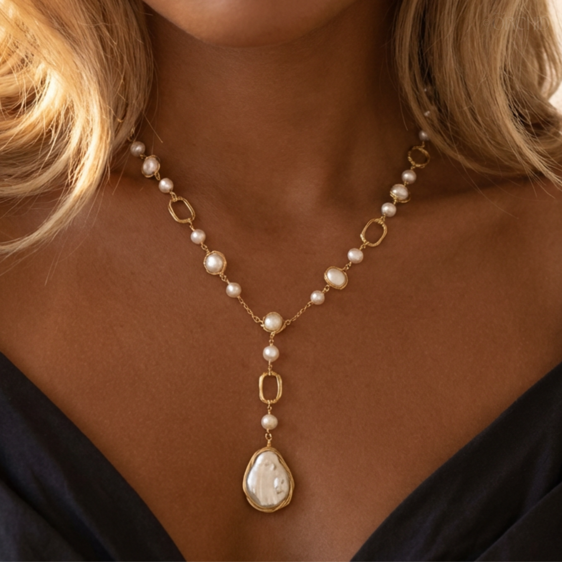 Pearl necklace with gold accents on a person wearing a black top.
