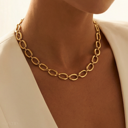 Gold chain necklace worn by a person with a neutral background