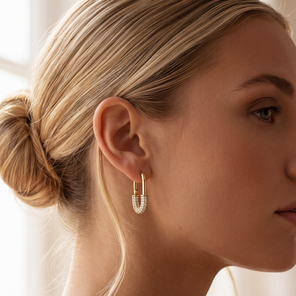 Close-up of a woman wearing gold hoop earrings with a blurred background