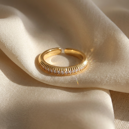 Gold ring with small diamonds on a beige fabric background