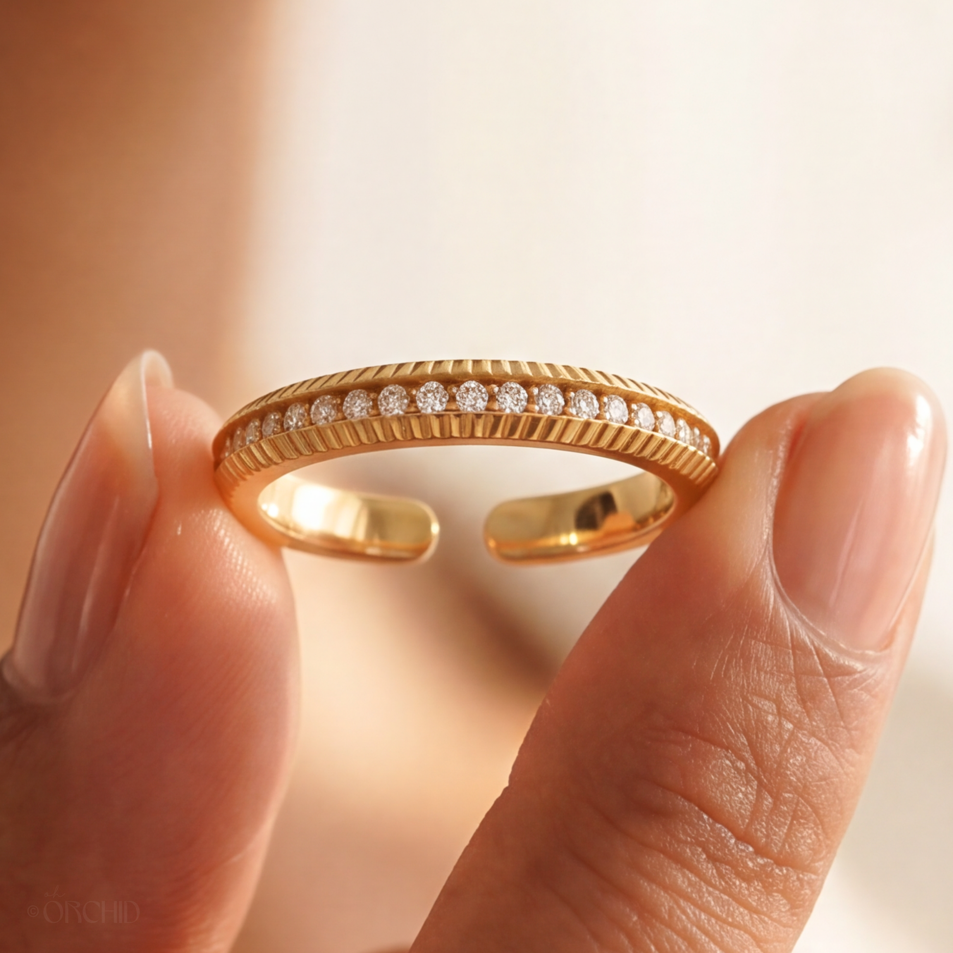 Gold ring with diamonds on a finger against a neutral background