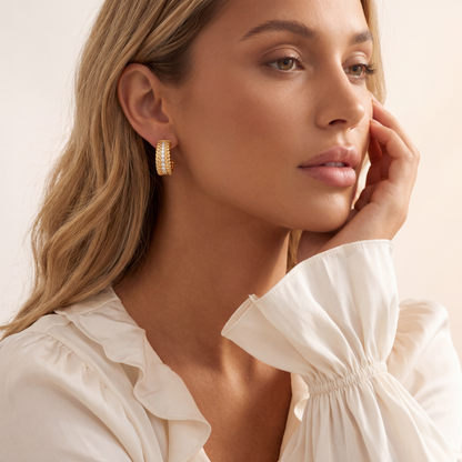 Woman wearing gold hoop earrings with a neutral background
