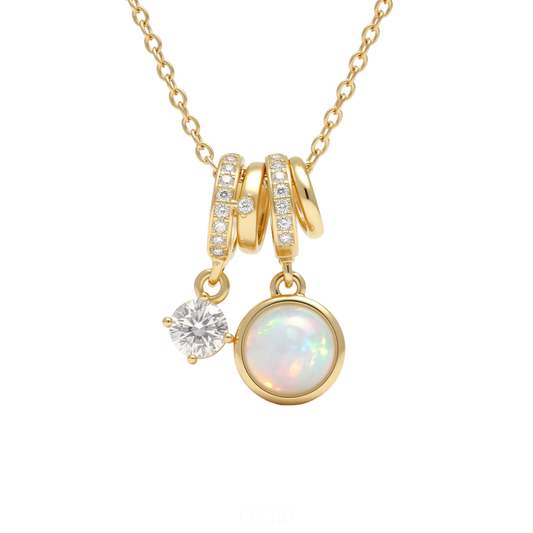 Gold necklace with opal and charm pendants on a white background