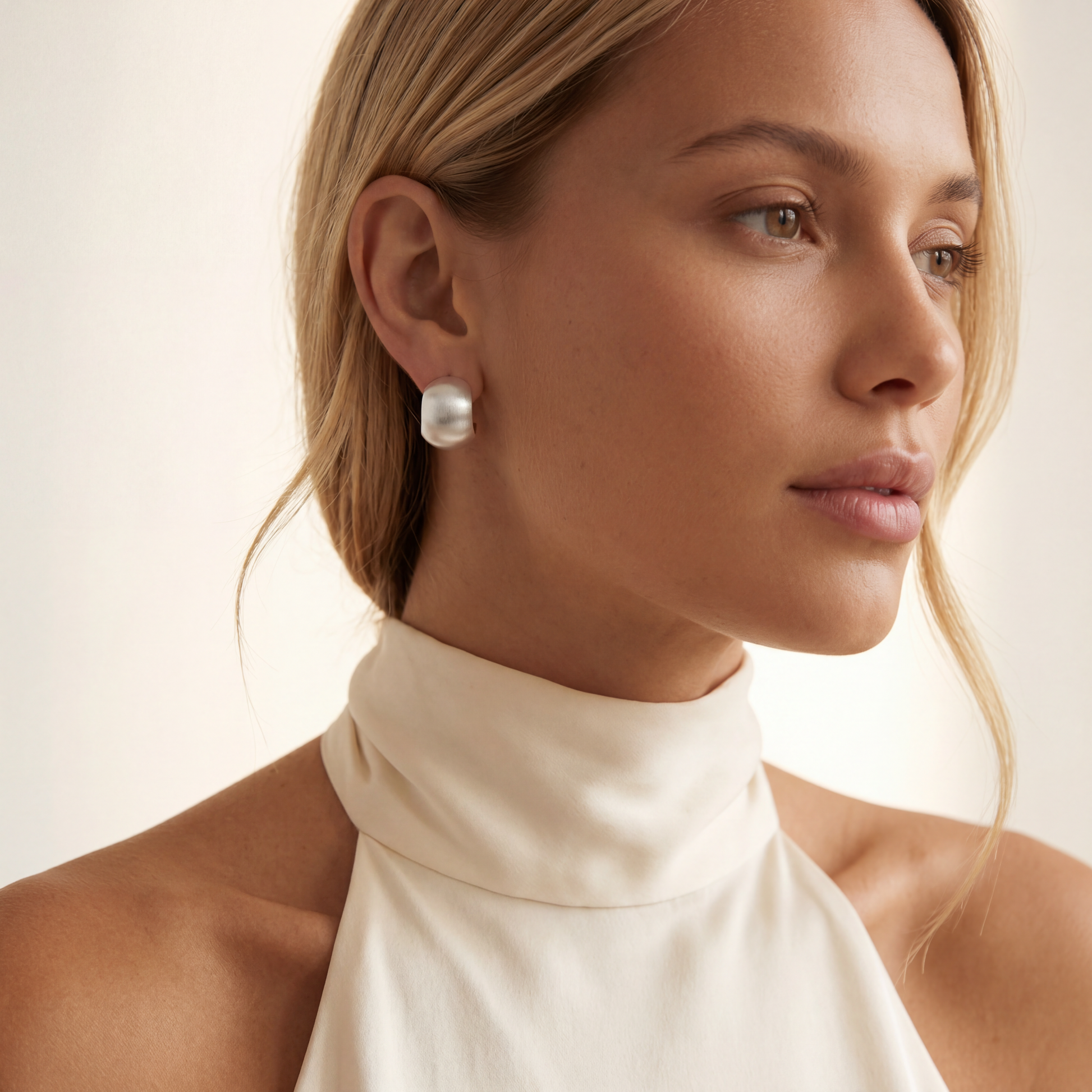 sterling silver hoop earrings worn by a woman with a neutral background