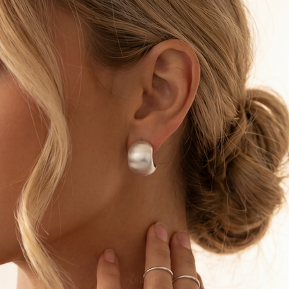sterling silver hoop earrings worn by a woman with a neutral background