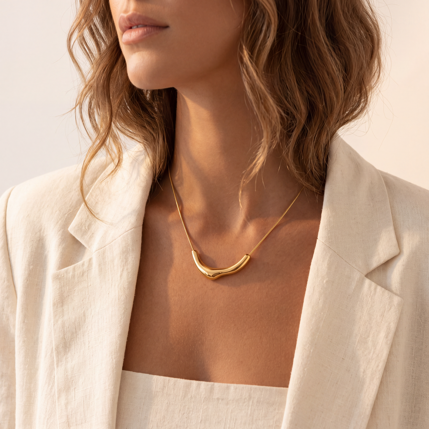 Woman wearing a gold necklace with a neutral background