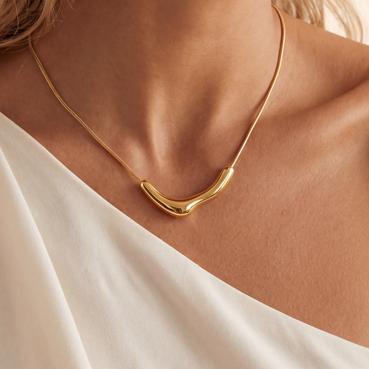 Gold necklace on a person wearing a white top