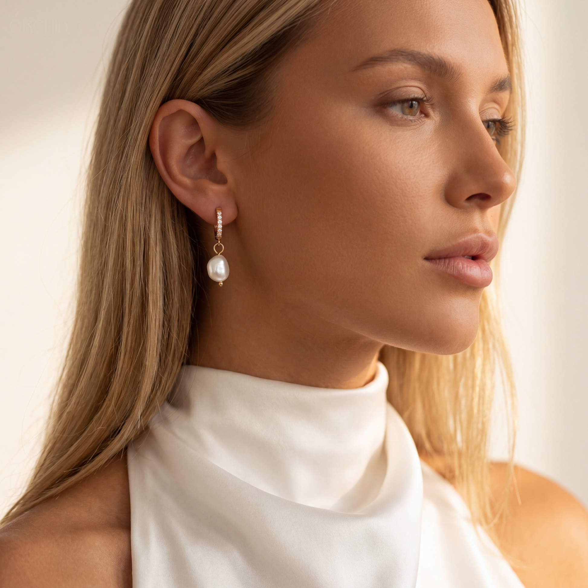 Close-up of a woman wearing pearl earrings with a neutral background