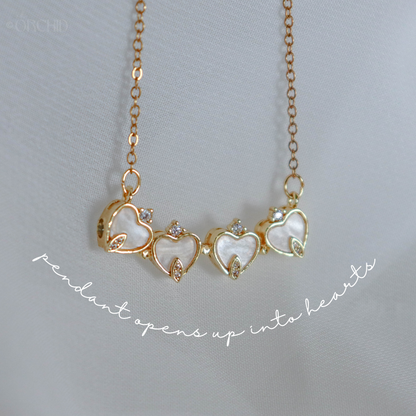 Gold necklace with heart-shaped pendant on a light gray background