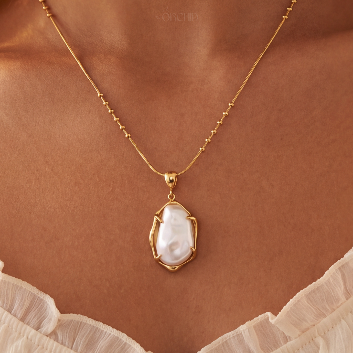 Gold necklace with a pearl pendant on a brown background